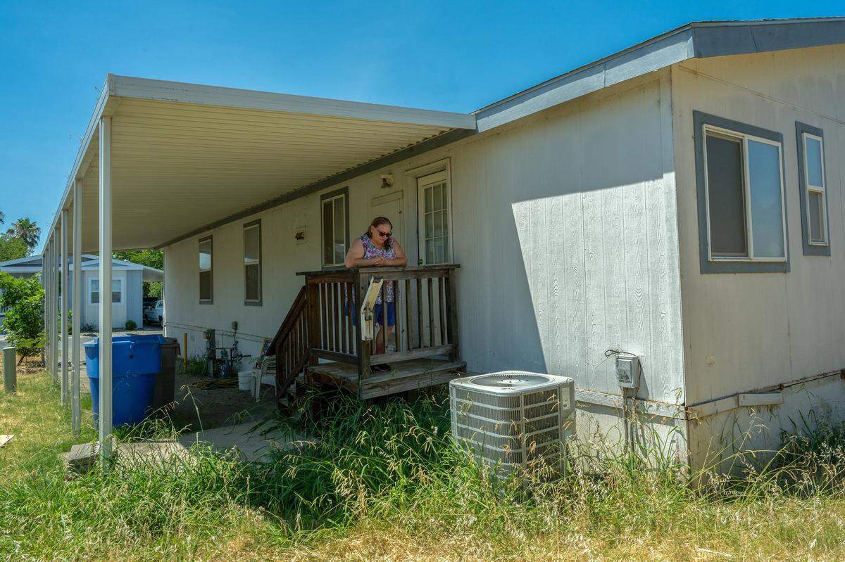 Marcie Del Nero stands on Tuesday, July 9, 2024, looking down at the air conditioner that Kevin Gerhardt, who died of heat stroke days before, could not afford to fix at the North Sacramento mobile home park where he lived with his disabled brother. “They said his organs shut down,” she said. Del Nero is now trying to find a facility for Gerhardt’s disabled brother James.