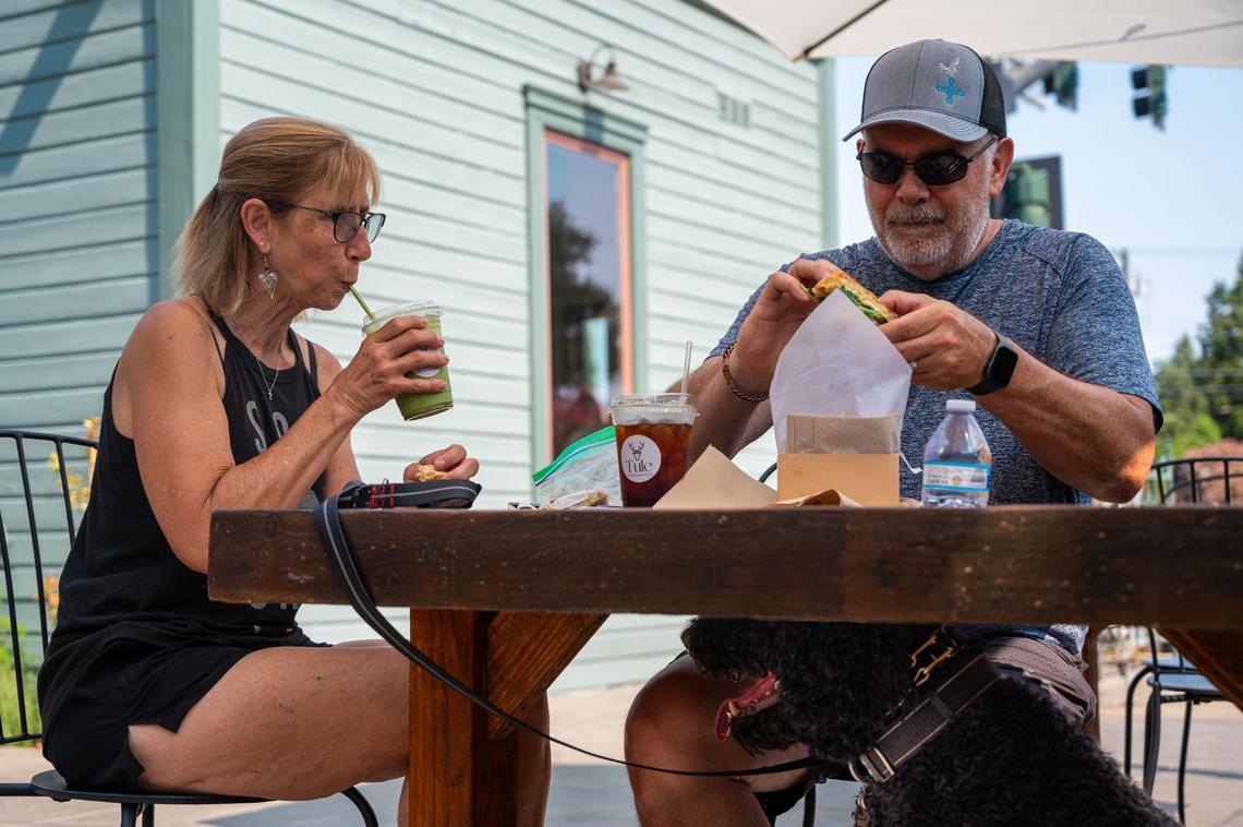 Elk Grove residents Margie and Michael Junker, accompanied by their dog Bosco, sit outside Tule Coffeehouse in Elk Grove on Saturday, July 20, 2024. “We love it here, it has a wonderful vibe,” Margie Junker said.