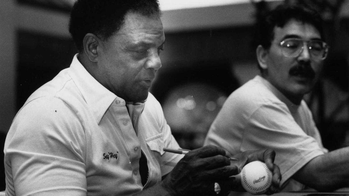 Willie Mays signs baseballs for fans during an appearance at a baseball card show at Fashion Fair Mall in an undated photo. The Hall of Famer center fielder and a slugging icon died Tuesday, June 18, 2024, at the age of 93, the Giants organization announced.