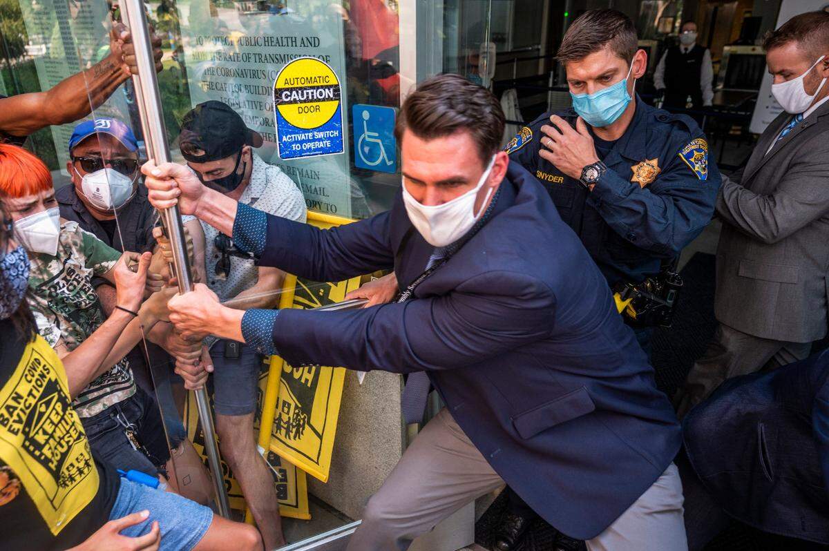 Protesters calling for the ban of COVID-19 evictions, try to enter the Capitol as guards attempt to pull the doors closed, Wednesday, Aug. 26, 2020, in Sacramento.