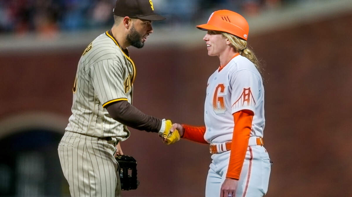 San Diego Padres’ Eric Hosmer (30) greets San Francisco Giants first base coach Alyssa Nakken in the fourth inning of a MLB game at Oracle Park in San Francisco on Tuesday, April 12, 2022.