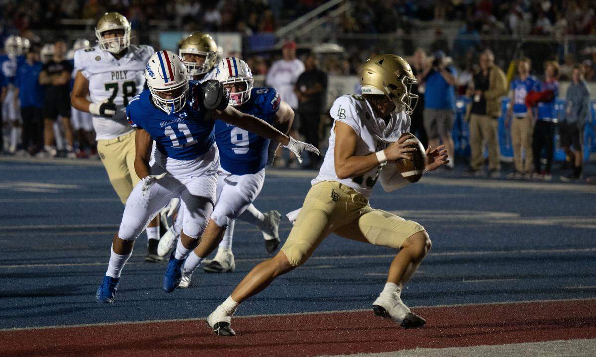 Under pressure by the Folsom Bulldogs’ Demetrione Brown (11) and Theo Greule (9), Long Beach Poly Jackrabbits quarterback Colin Creason (13) prepares to throw away the ball on Friday, Aug. 23, 2024. The Bulldogs were awarded a safety on the play.