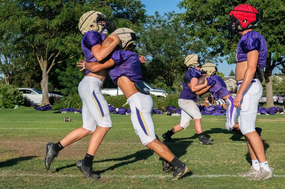 Football players practice tackling at Bradshaw Christian High School in Vineyard earlier this month while wearing Guardian Caps over their helmets as a concussion safety measure.