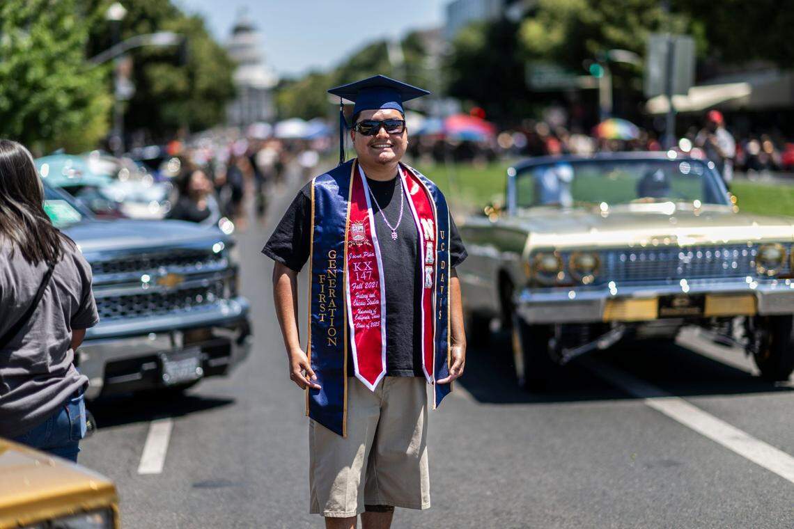 Josue Piña, a recent graduate from UC Davis with a double major in history and Chicano studies, stands in front of classic cars during the California Lowrider Holiday Celebration on Sunday on Capitol Mall. Piña said he did research on the history of lowriding in Sacramento.
