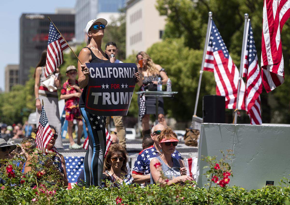Demonstrators look toward the American flag flying over the state Capitol during a protest against Gov. Gavin Newsom’s coronavirus stay-at-home order Thursday, May 7, 2020 in Sacramento during the coronavirus pandemic.