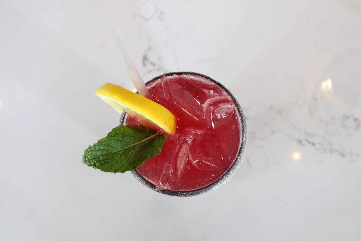 The Back Beam cocktail at Back Bistro in Folsom’s Palladio shown from above on Monday, April 24, 2023. It contains gin, fresh lemon, fresh lime, house-made blueberry puree, and a sugar rim, lemon and mint garnish.