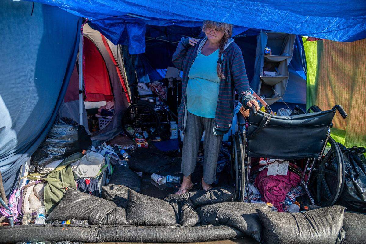 Wendy Corron, 54, stands behind sandbags on Monday, Oct. 25, 2021, that she said she purchased during Sunday’s record-setting storm. Her tent at the Safe Ground homeless encampment at Eighth and W streets still flooded.