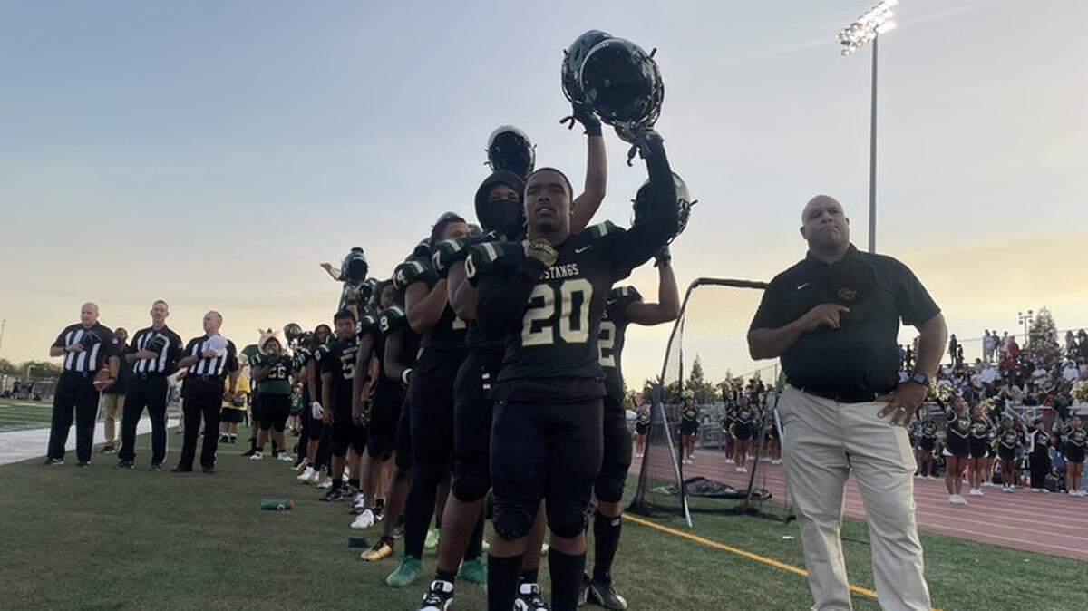 Monterey Trail Mustangs raise their helmets during the national anthem on Friday. The Mustangs lost to the Pittsburg Pirates, 42-13.