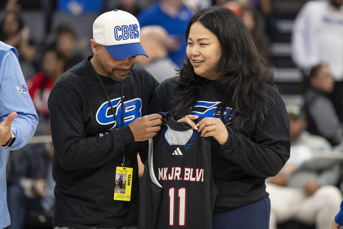 Christian Brothers boys coach Jermaine Brown holds a jersey honoring Jaden DeJesus-Eves with Jaden’s mother, Jamie, after the CIF Sac-Joaquin Section Division II girls basketball championship at Golden 1 Center in Sacramento on Friday. DeJesus died earlier this week.