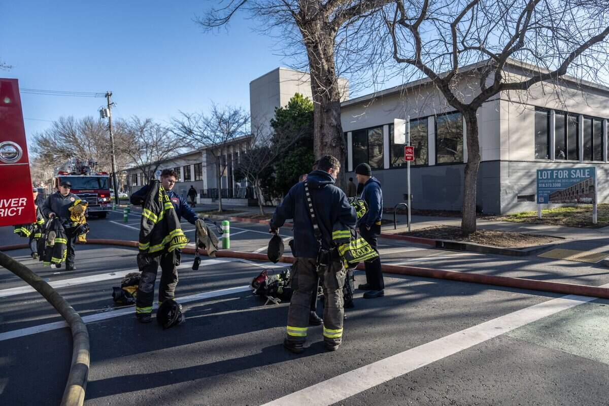 Sacramento firefighters stand outside a vacant building at 19th and J streets that burned on Tuesday in midtown. A male, a female and a dog were found dead inside the building after an early morning fire.
