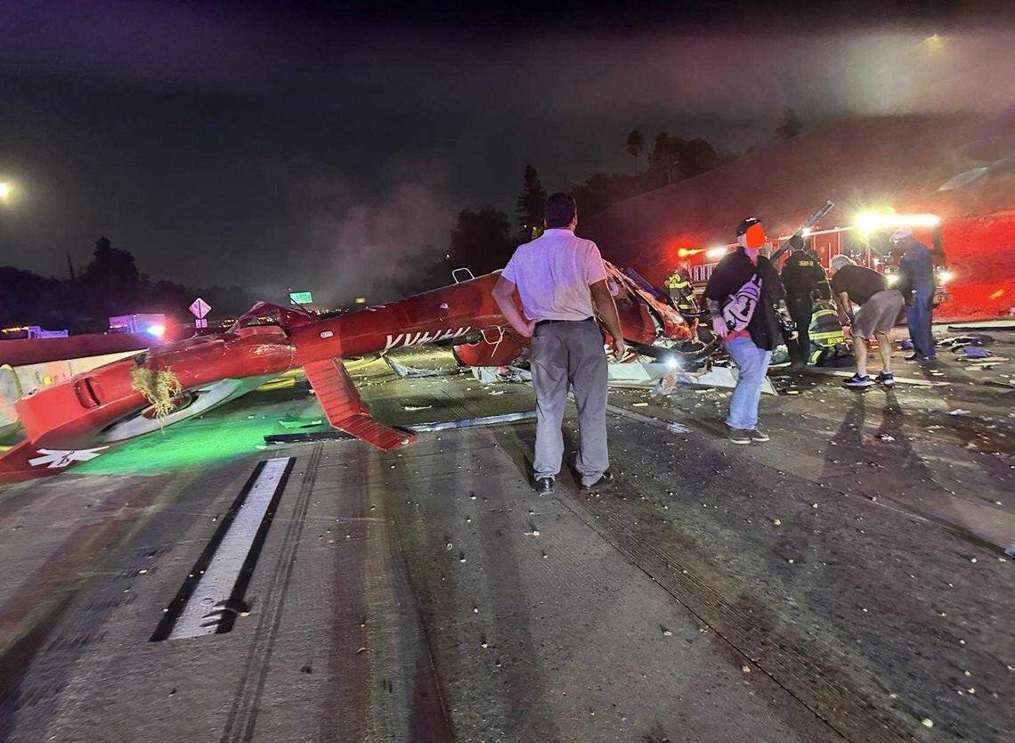 First responders and motorists are seen on lanes of Highway 50 after a medevac helicopter crashed Monday. The helicopter that crashed onto freeway lanes was operated by Reach Air Ambulance Services.