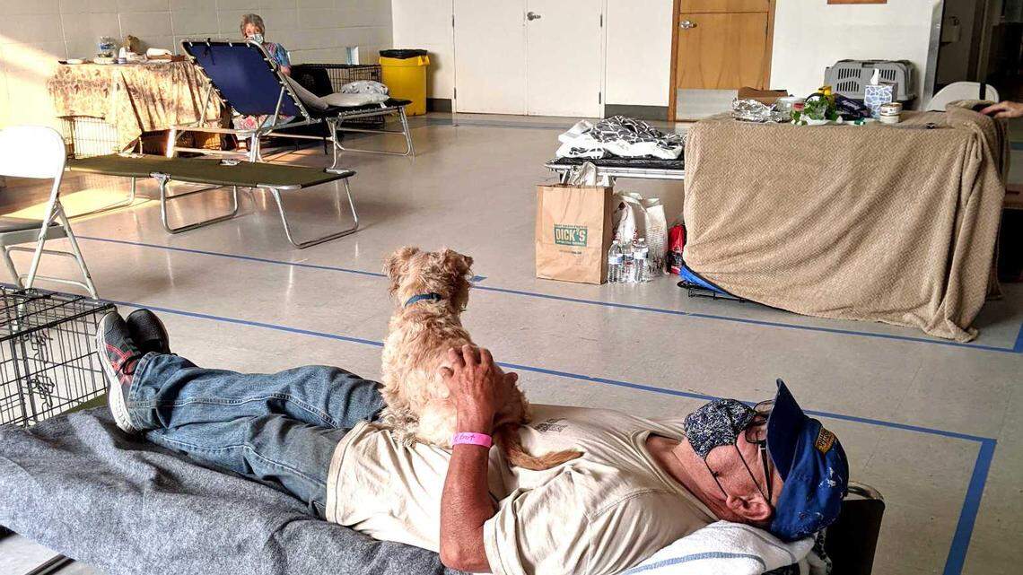 Bart Pettijohn rests on his cot with his dog, Clumsy, in an evacuation center at the Petaluma Veterans Memorial Building on Sept. 30. Volunteer health care workers and a veterinarian were among those who checked up on dozens of seniors and pets forced out of their homes during the biggest wildfire season in California history. 