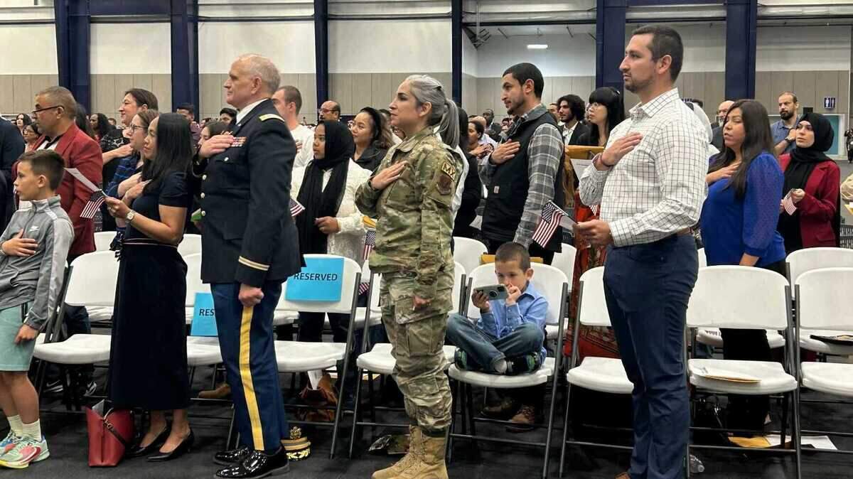 A family stands in honor of pledge allegiance during the Independence Day-themed naturalization ceremony that welcomed over 800 new U.S. citizens.
