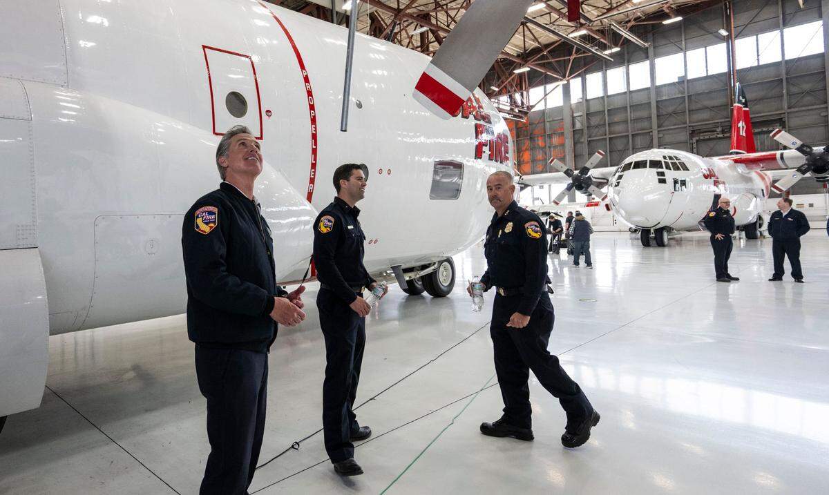 Gov. Gavin Newsom looks under a wing of Cal Fire’s new C-130H firefighting airplane during a press conference at McClellan Park on Thursday.