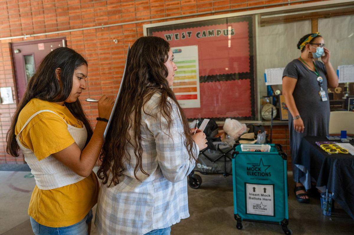 Seniors Marianna Sosa, 17, leans on classmate Jasmin Aceves, 17, as she fills out a form to preregister to vote after participating in a mock election event at West Campus High School in Sacramento on Wednesday, Oct. 2, 2024. The simulation they participated in during their government class was run by the county elections office. "It was a good format to have at school so we could ask questions,” said Sosa.