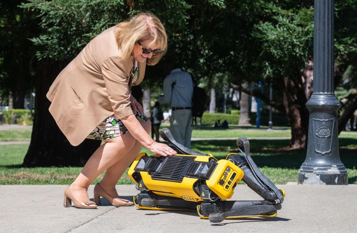 Assemblywoman Emerita Eloise Gómez Reyes, D-Colton, gives Boston Dynamics robot dog Spot a “belly rub” outside the state Capitol on Thursday.