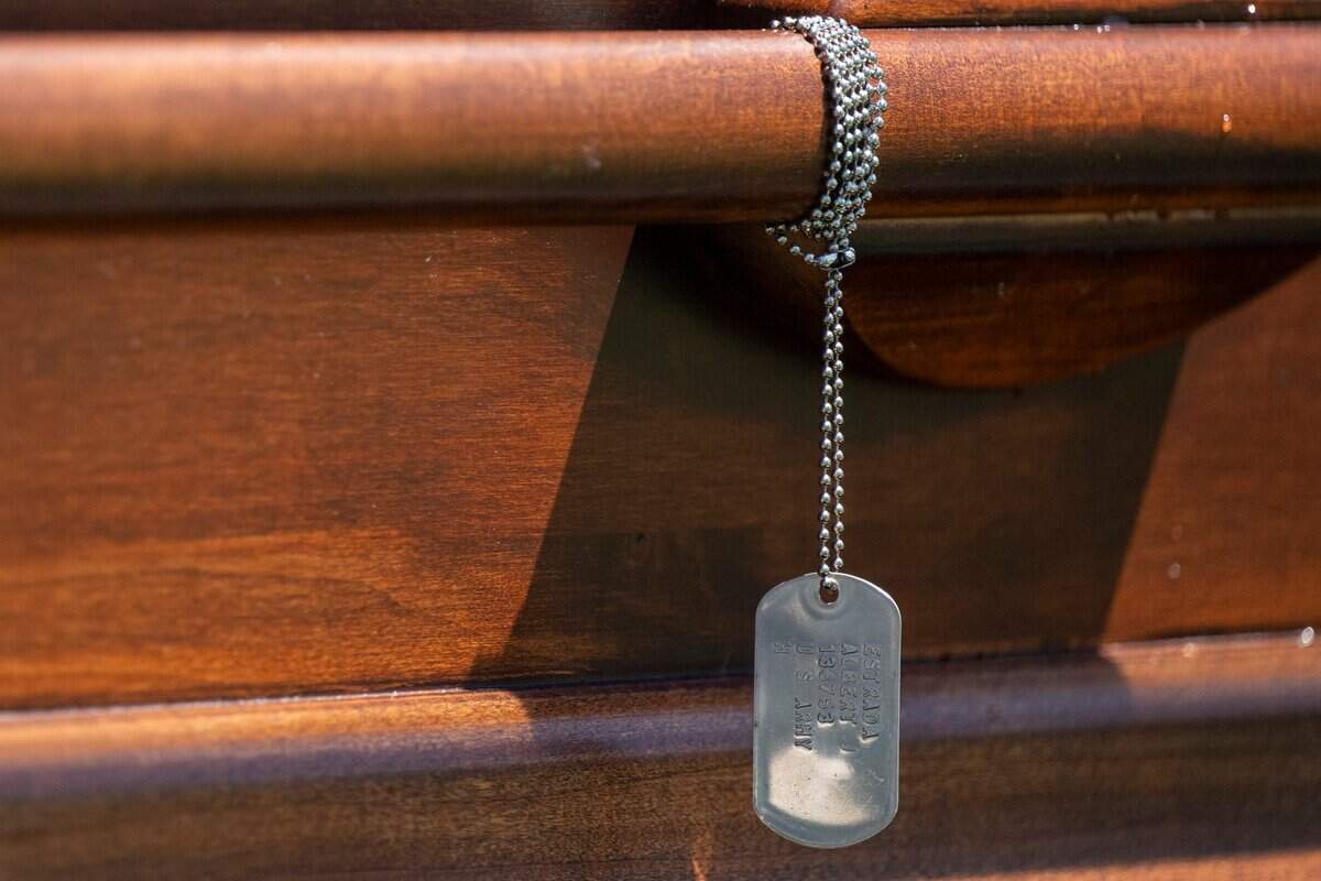 A dog tag is attached to Cpl. Albert Estrada’s coffin before he is laid to rest at St. Joseph’s Cemetery in Woodland.