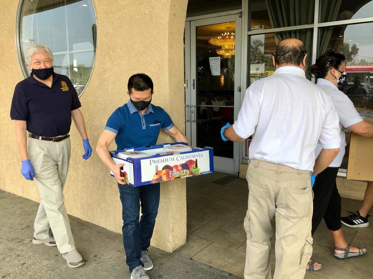 Kevin Thai, deputy director of the Sacramento Chinese Community Service Center, takes a carton of boxed lunches from a CACS volunteer.