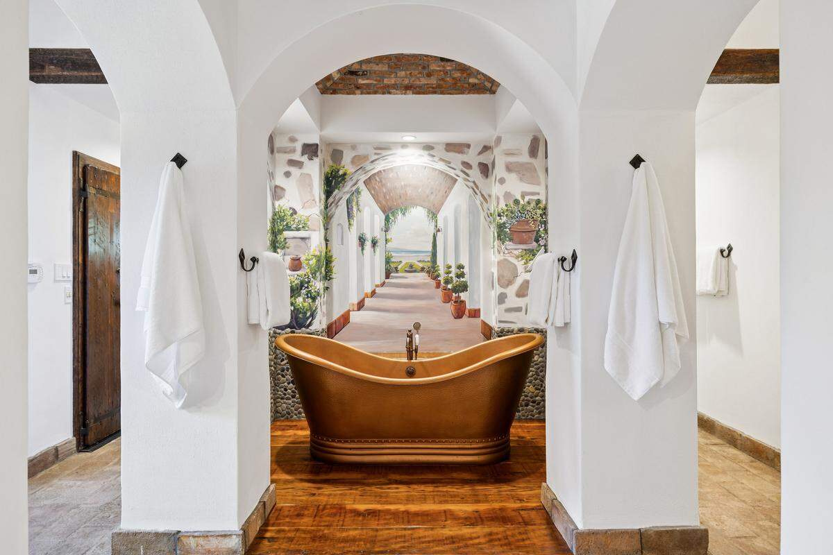 The wellness part of the estate includes an expansive fitness pavilion with sauna and Tonal strength training system, connected to the luxurious primary bath with oversized shower and double slipper copper bath tub, and opening onto the pool and spa with outdoor grotto and shower.