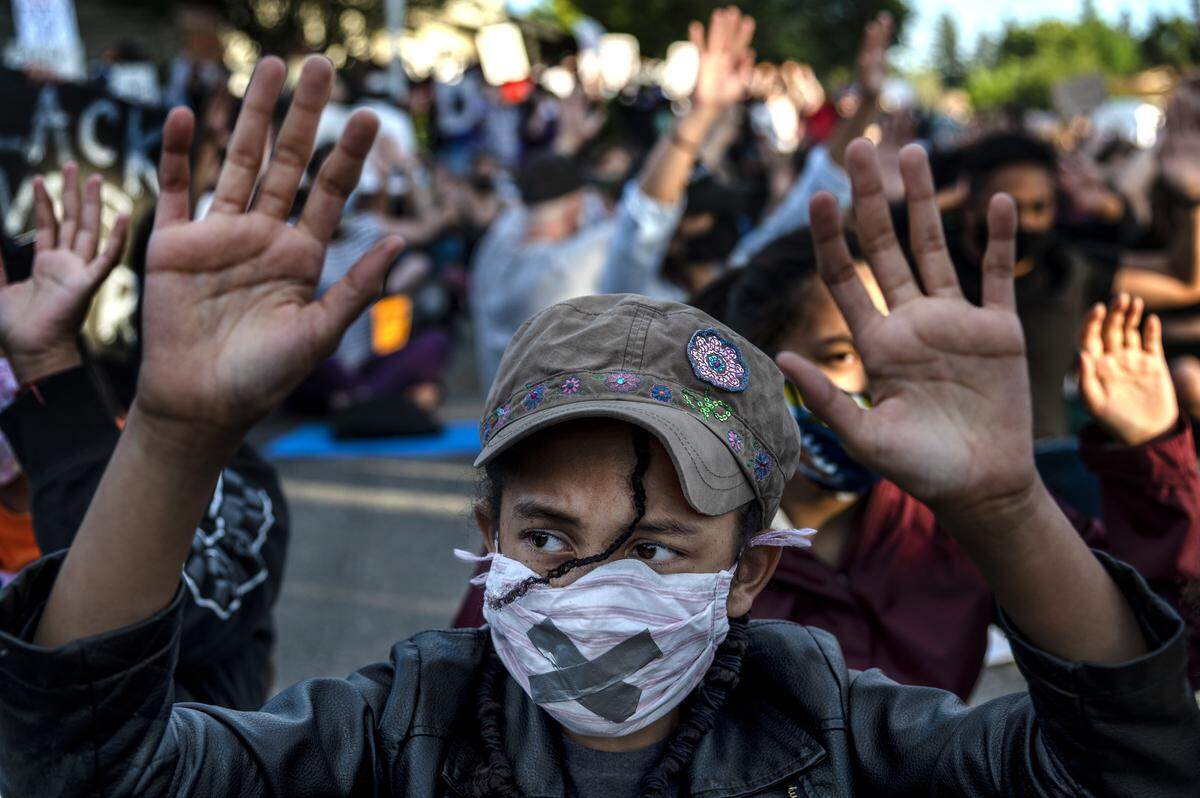 Bella Fernadez, wears a mask with an X to symbolize “I can’t breathe,” holds up her hands during the chant “Hands up don’t shoot,” at a Black Lives Matter Sacramento ‘die-in’ on Friday, June 5, 2020 in the Pocket neighborhood, near the home of Sacramento Mayor Darrell Steinberg.