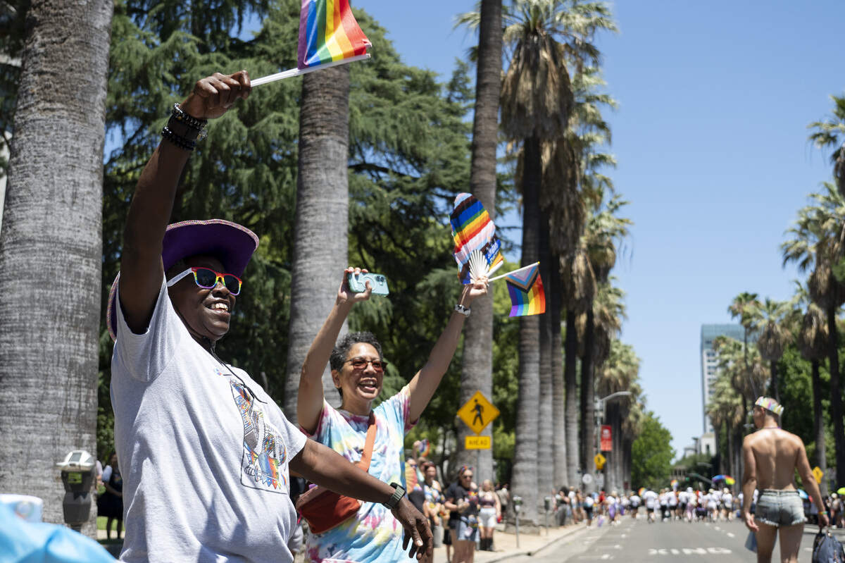 LaTanya Dukes, left, waves pride flags during the Sacramento Pride Parade in Sacramento on Sunday, June 14, 2026.