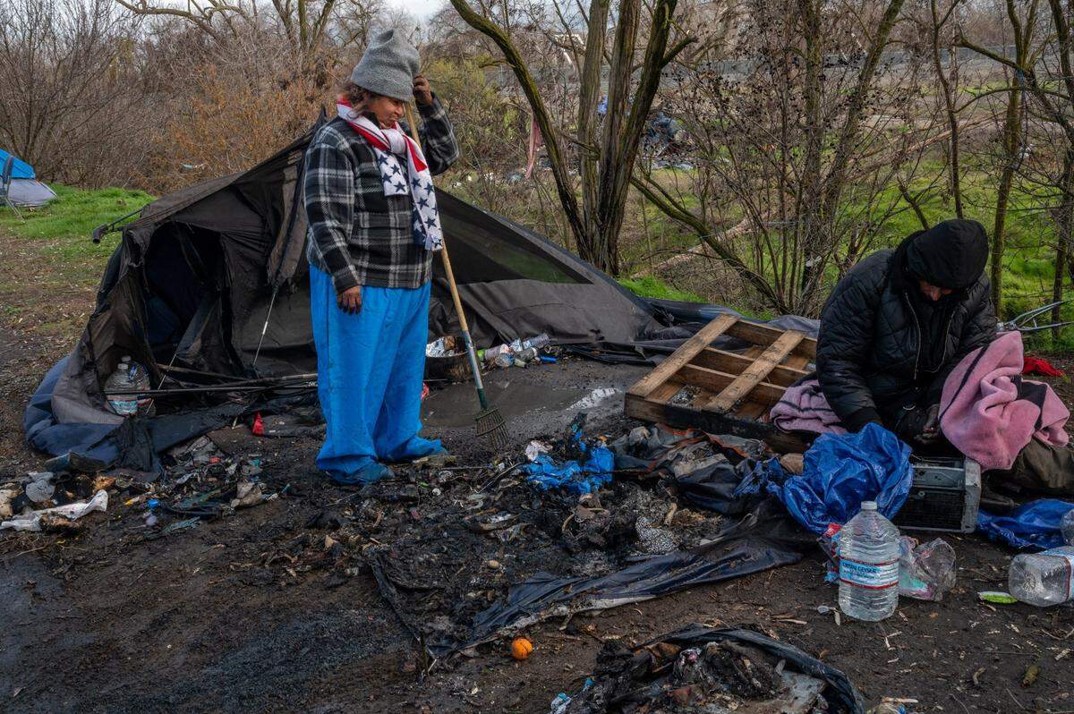 Leora Sorondo, 64, and her son Albert Sorondo, 47, sift through what is left after their tent burnt last night during the wind storm at a homeless encampment near Basler and N. 18th streets in Sacramento on Wednesday, Jan. 27, 2021.