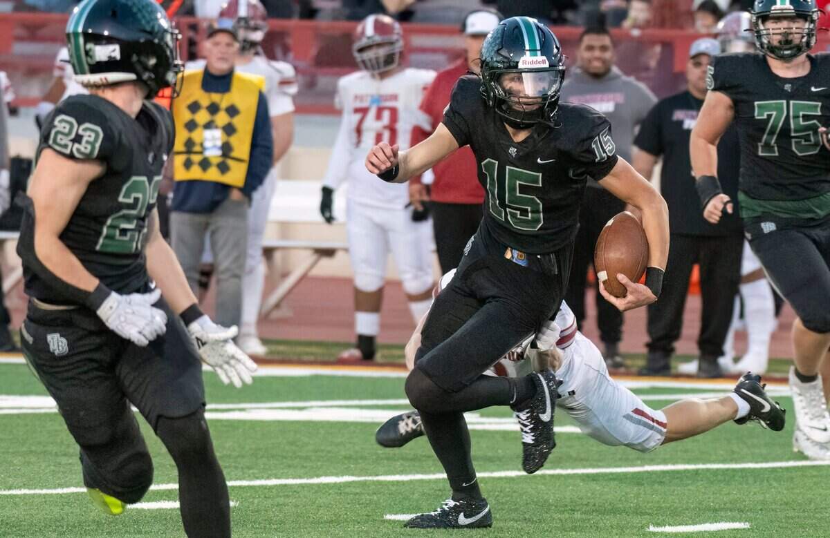 Twelve Bridges Raging Rhinos quarterback Connor Flaherty (15) runs for a first down against the Patterson Tigers during the Sac-Joaquin Section Division IV championship game at Hughes Stadium in Sacramento on Friday.