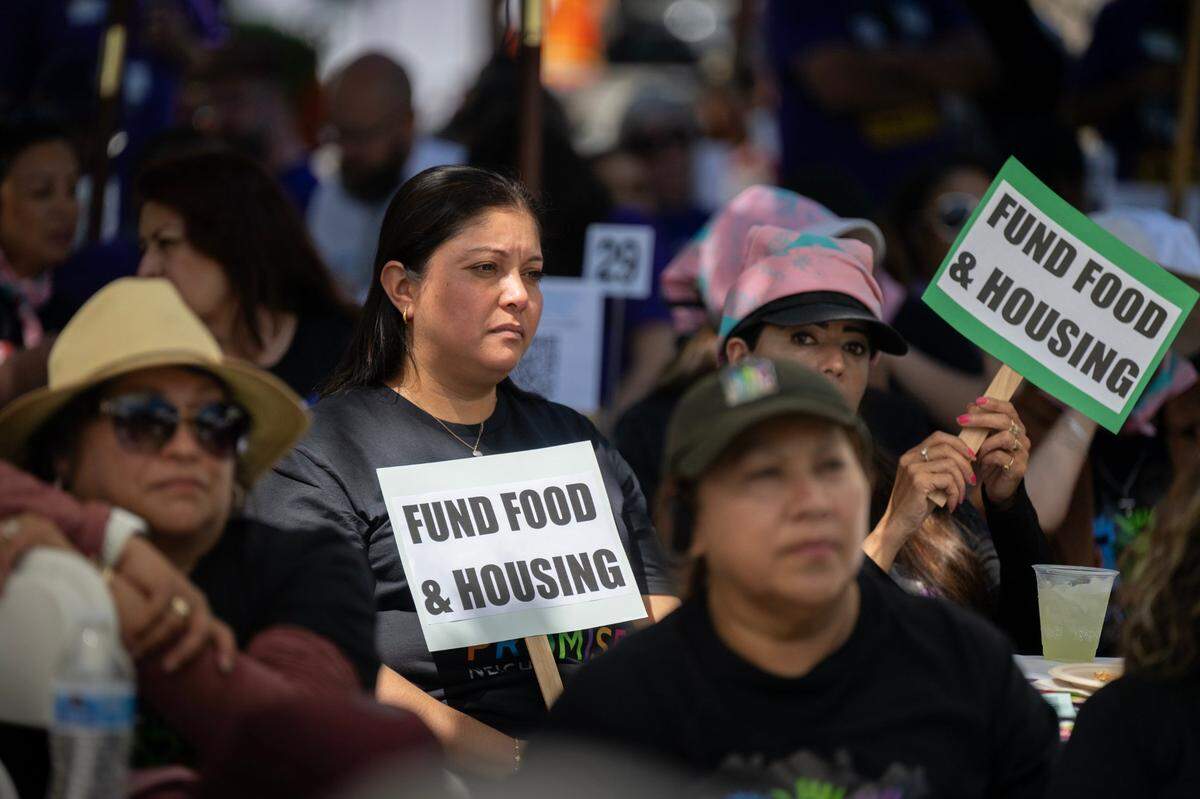 Fabiola Hercules and Leticia Arenas, members of community organization Hayward Promise Neighborhoods, hold signs and listen to speakers at a rally at the state Capitol on Wednesday with SEIU members and anti-poverty advocates asking for legislative support for those harmed by cuts proposed by Gov. Newsom’s May budget revision to address the state’s deficit.