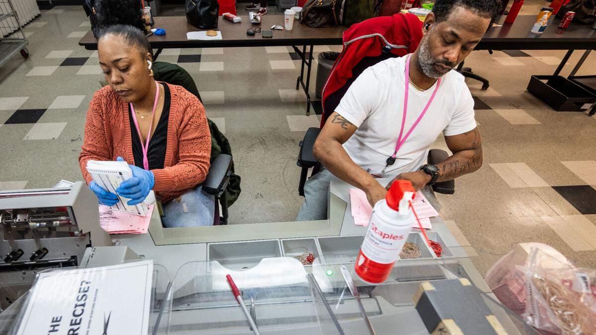 Ashliegh Jefferson and Sean Riley with the Sacramento County Voter Registration and Elections office separate ballots from their envelope after signatures were verified on Tuesday, Nov. 5, 2024.