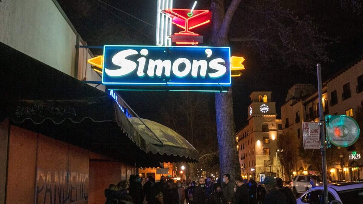 The neon sign of Simons Bar & Cafe is turned on as family and friends of Simon Chan, owner of iconic midtown Sacramento gathering spot, hold a candlelight vigil on Monday, March 8, 2021.