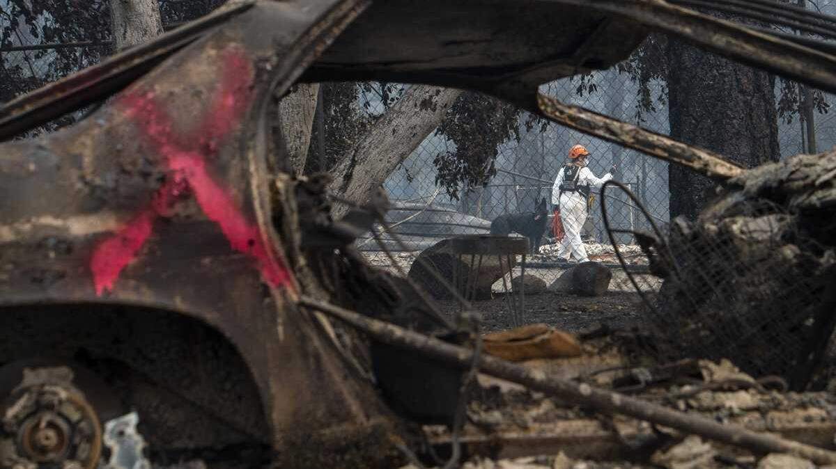 A search-and-rescue team search for remains in a residential area destroyed by the Camp Fire in 2018. Consumer advocates say California lawmakers and the state’s insurance commissioner are working on a deal to free up more coverage but at the cost of caving to insurers’ demands to loosen regulations and let them charge higher rates.