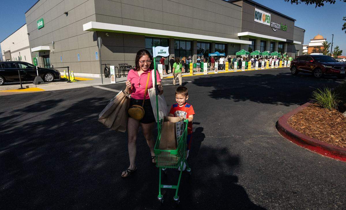 Elizabeth Piven of Citrus Heights and her four-year-old son Sean leave Amazon Fresh as more customers wait in line to enter Thursday, the store’s opening day.