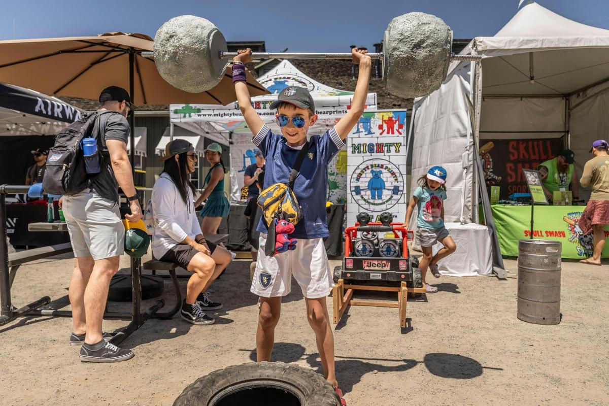 Elijah Dagger, 10 of Scotland, lifts a faux barbell at the Mighty Bear booth during the World’s Strongest Man competition on Sunday in Old Sacramento. Elijah and his family of four traveled to Sacramento to see the competition in person.