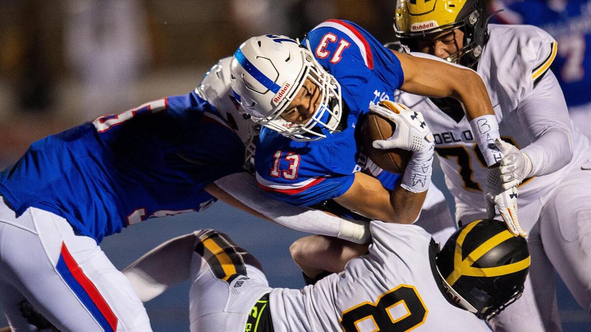 Folsom bulldogs’ Rico Flores Jr. gains yardage over Del Pro Golden Eagles’ Jacob Birch during a game at Folsom High School on Friday, March 26, 2021, in Folsom.