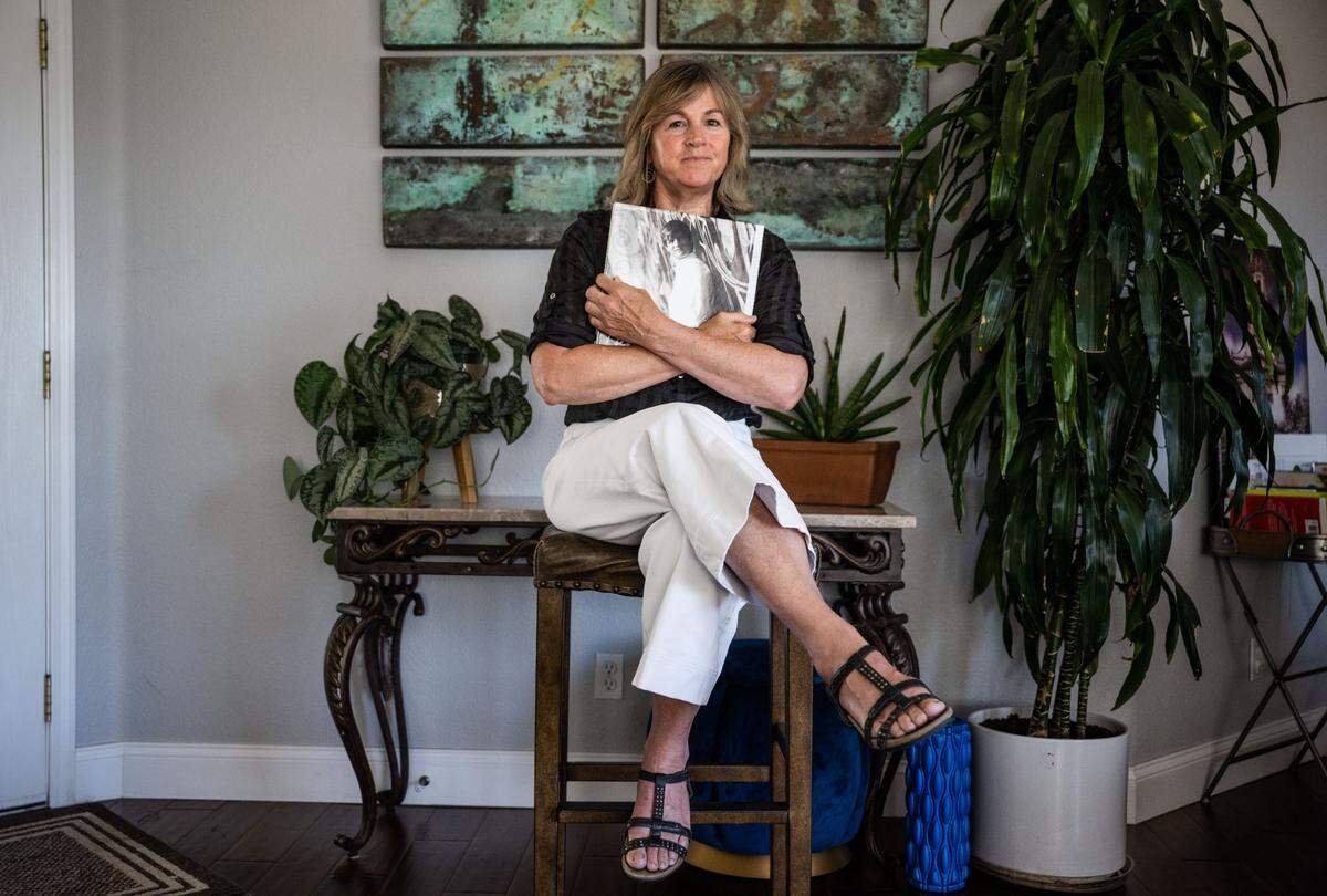 Deanna Hampton of Auburn holds a book on Thursday, July 27, 2023, with photos of her late son Trevor, who was abused by Father Michael Kelly at St. Andrews parish in San Andreas. Trevor testified about the abuse before a grand jury in 2014, but died in a tragic accident before Kelly could be brought to trial.