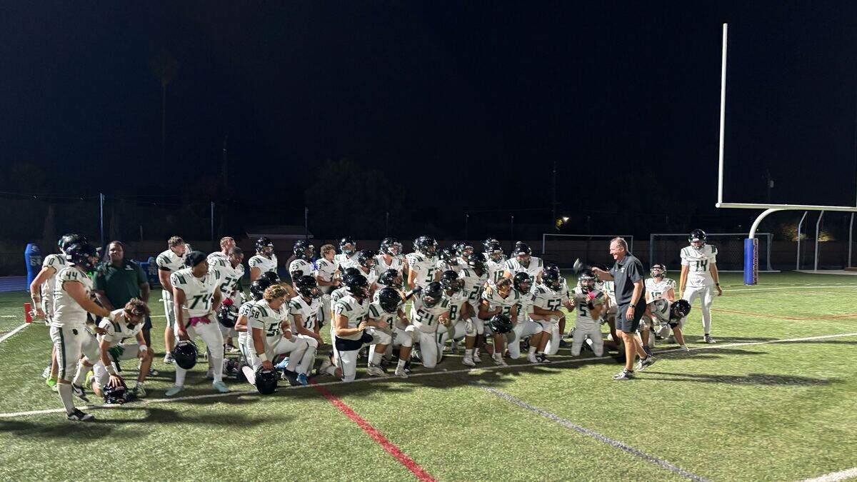 Twelve Bridges High School coach Chris Bean tips his hat and addresses his team after the Raging Rhinos defeated the Falcons, 42-7, Friday at Christian Brothers High School in Sacramento.