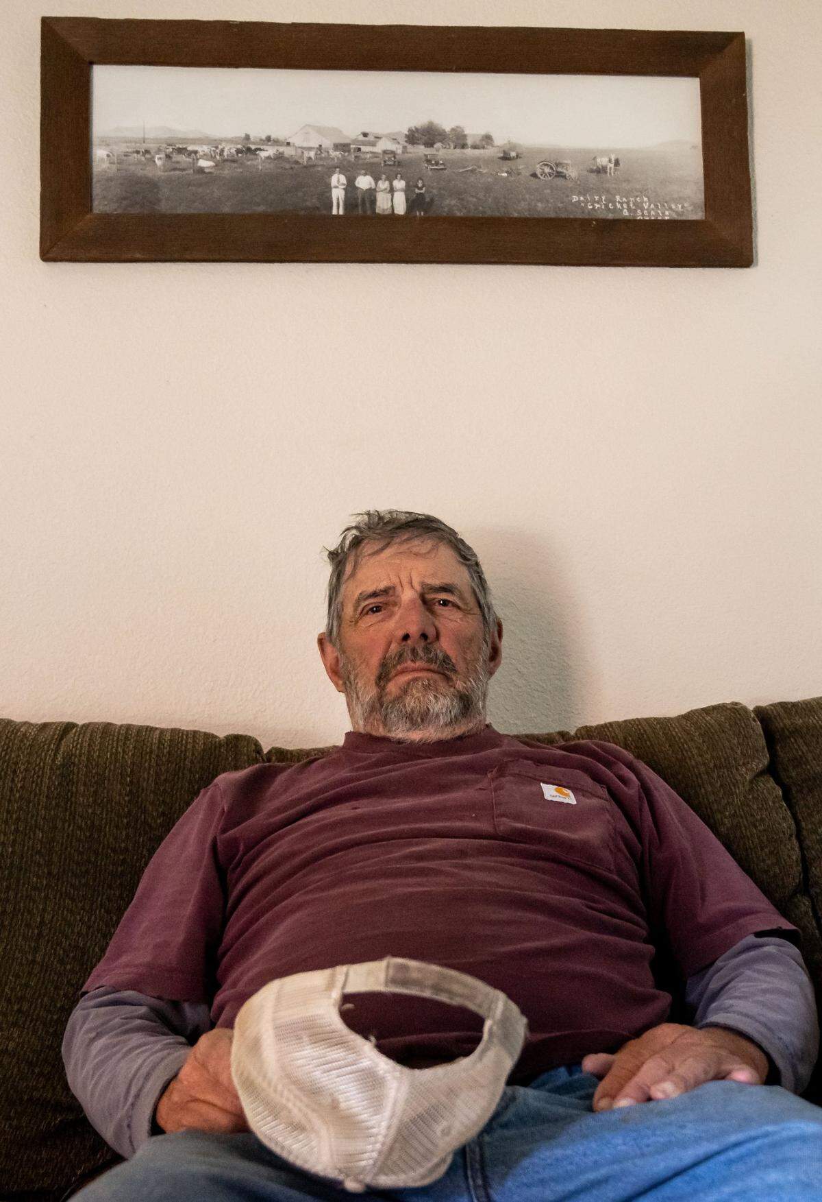 Cattle rancher Jim Scala sits at home under an old photograph of his family, which bought his ranch near Montague in Siskiyou County in 1915.