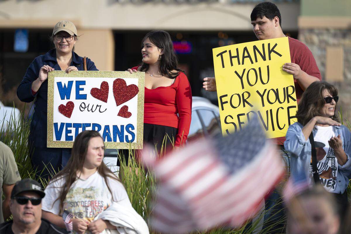 Parade watchers hold signs during a Veterans Day parade in Folsom on Tuesday, Nov. 11, 2025.