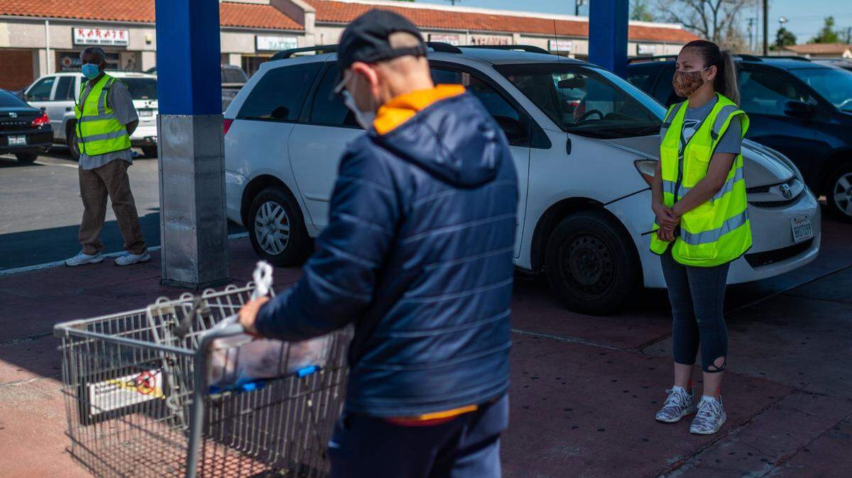 Stockton Boulevard Association volunteer Selena Zuniga, right, and Ernest Maharaj stand outside Wing Wa Seafood Supermarket near Stockton Boulevard in Sacramento on Thursday, April 8, 2021. Due to the spike in AAPI hate crimes in the United States, the Stockton Boulevard Association launched “Safety on Stockton,” a volunteer buddy program to keep an eye on Asian elders who may become the target of crime.
