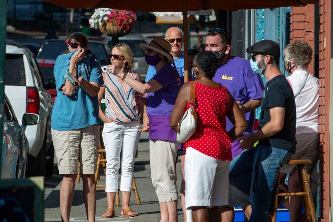 People gather along the store fronts on Main Street in downtown Placerville on Friday, June 26, 2020. California has ordered everyone to wear a face mask while in public as it continues to try and re-open after more than three months of lockdown during the coronavirus pandemic.