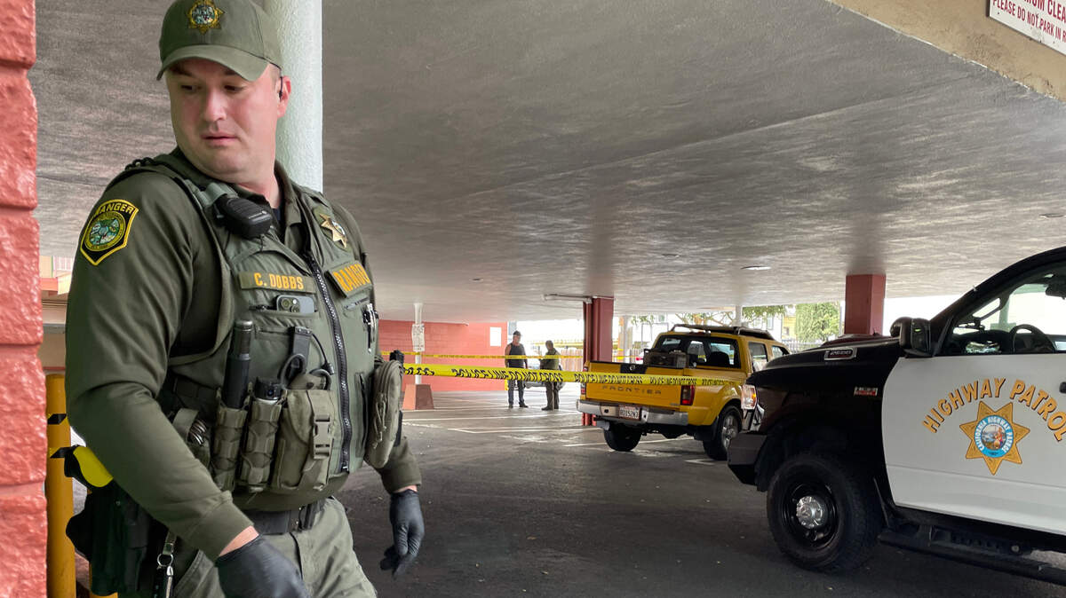 Sacramento Park Ranger Dobbs unspools crime scene tape around the yellow Nissan pickup truck involved abandoned on Alhambra Boulevard after a carjacking in Sacramento on Friday.