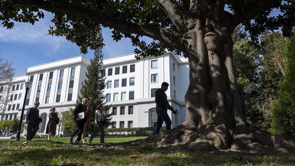 A group of people walk past the Capitol Annex in 2020. California state office buildings will set thermostats at 78 degrees Tuesday at 4 p.m. and 80 degrees at 5 p.m., Gov. Gavin Newsom’s spokeswoman said.