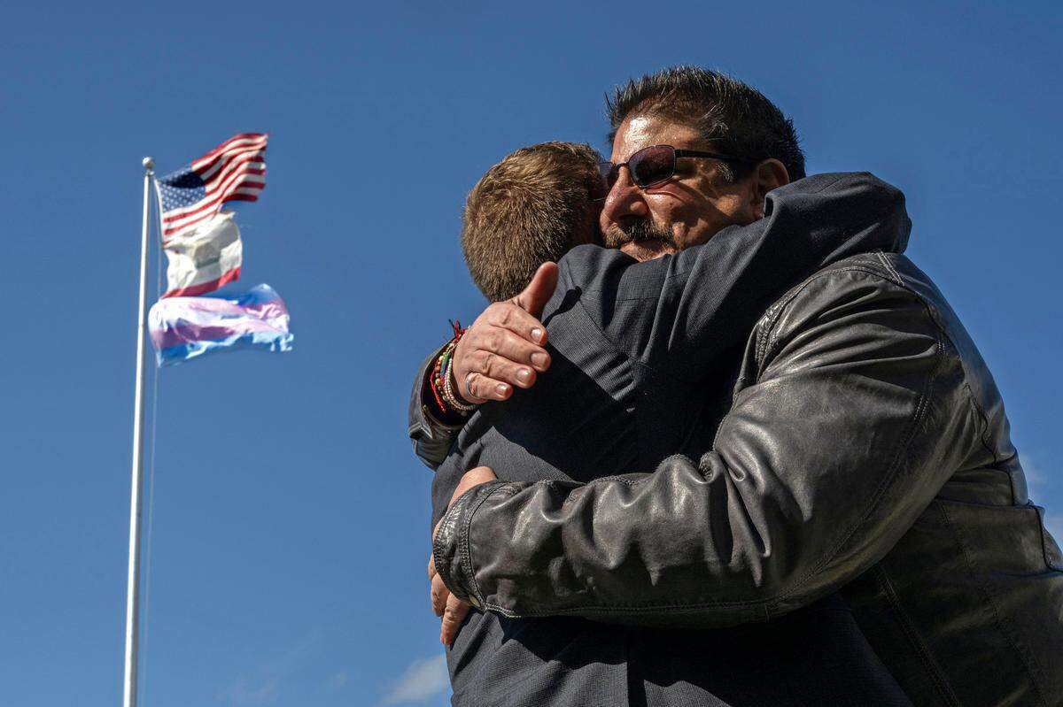 Sacramento County Supervisor Phil Serna, right, embraces transgender advocate Evan Minton, who coordinated the event, to celebrate the raising of the transgender flag at Sacramento City Unified School District headquarters on Monday, March 20, 2023, in observance of the Trans Day of Visibility. The district’s offices are named after Serna’s parents.