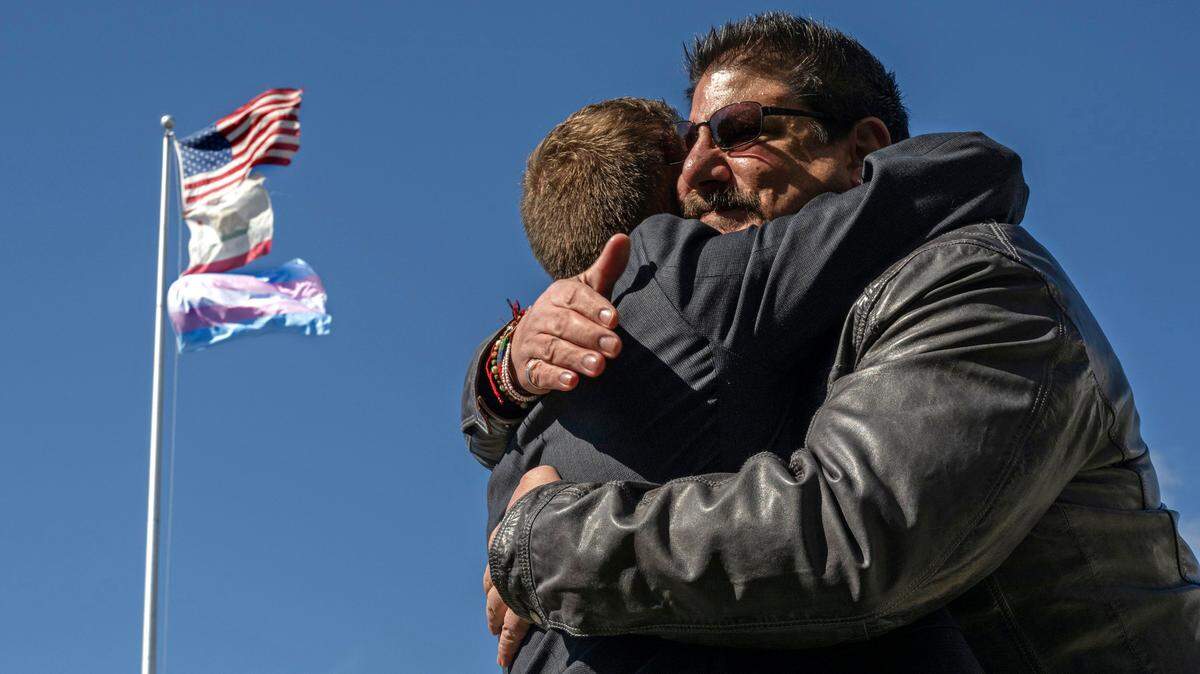 Sacramento County Supervisor Phil Serna, right, embraces transgender advocate Evan Minton, who coordinated the event, to celebrate the raising of the transgender flag at Sacramento City Unified School District headquarters on Monday, March 20, 2023, in observance of the Trans Day of Visibility. The district’s offices are named after Serna’s parents.