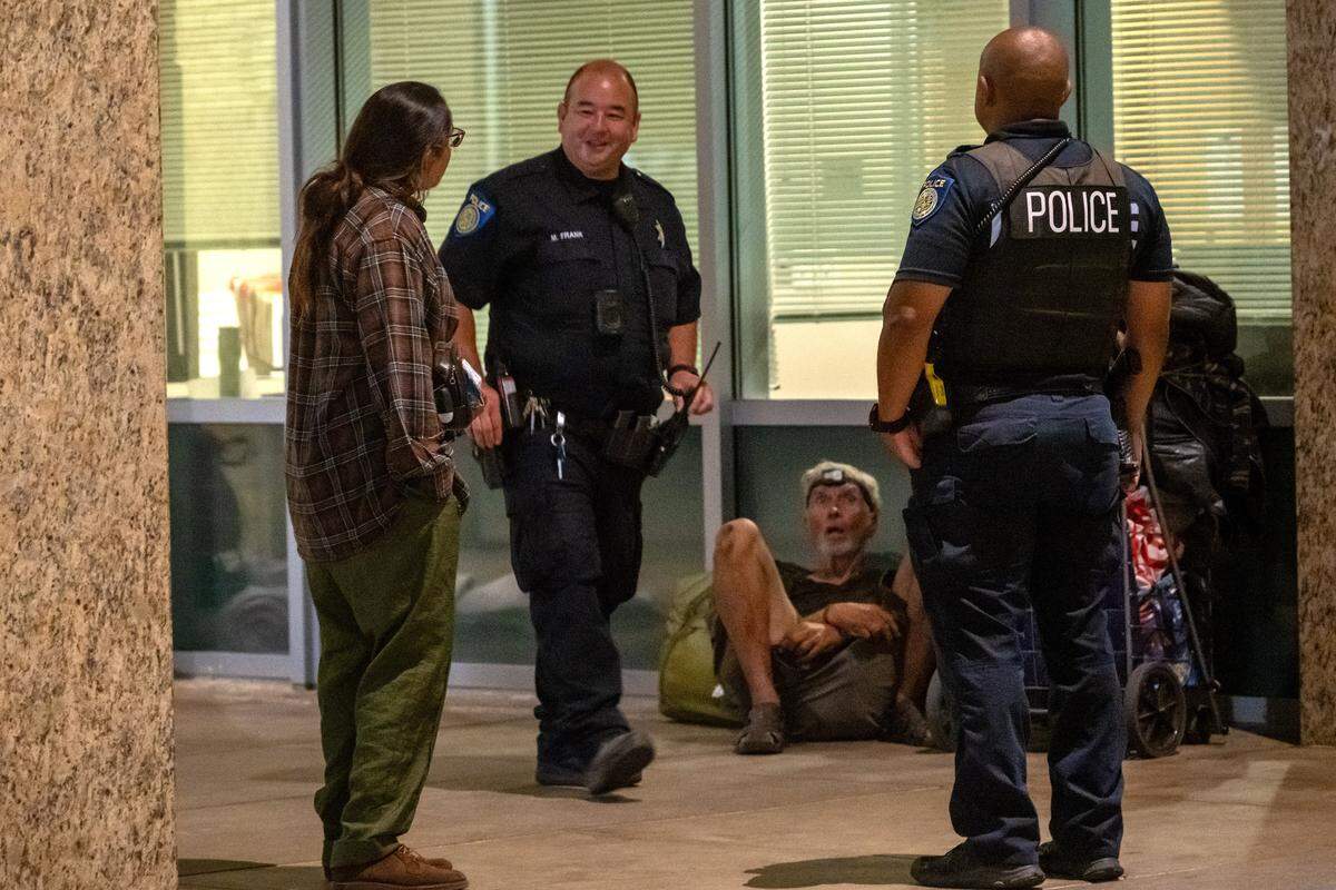 The Sacramento Regional Coalition to End Homelessness’ Niki Jones, left, demands to know where the city plans to house Randy Horn, 72, seated, who has been regularly sleeping outside City Hall, on Wednesday. “Where are they supposed to go, Frank?” she shouted several times to Sacramento Police Officer Marcus Frank, center. Officers were warning the homeless that they would be ticketed at 6 a.m. if they were still there.