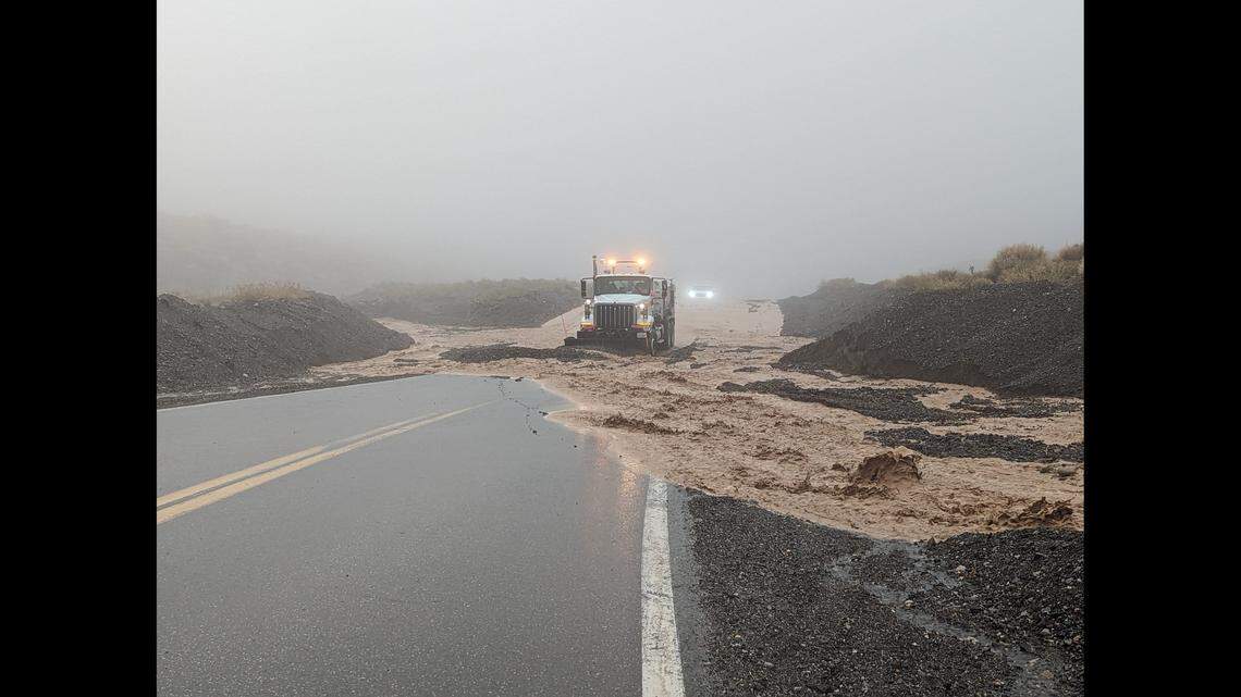 A truck works to clear rocks, mud and floodwater from CA 190.