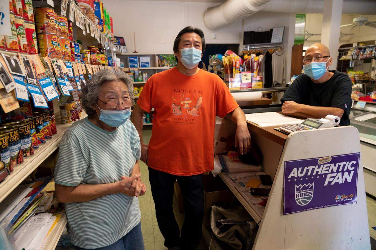 Arvella Fong, 89, and her sons Kenton, 66, and Dennis, 57, stand in Sam’s Market in 2020, which has been in their family since 1941. The small corner store in downtown is filled with old memorabilia like an ancient wooden cash register from 1941.
