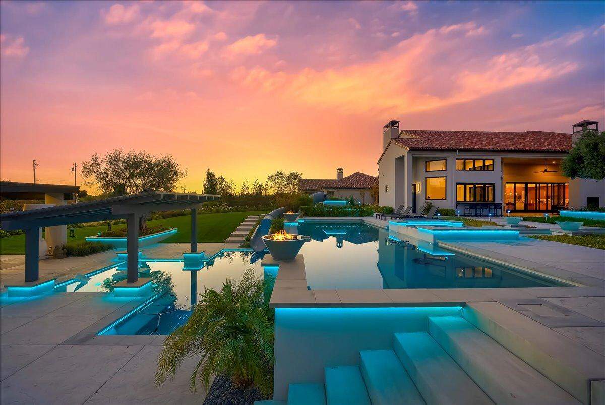 The Granite Bay home on the market for $8.2 million features a resort-style backyard with a reflection pool flowing to dual swimming pools and spa with a waterslide, surrounded by fountains and fire pits.