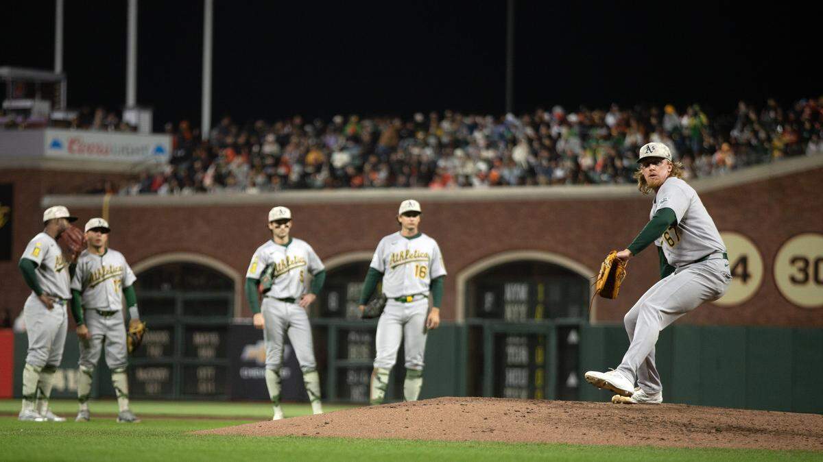 May 16, 2025; San Francisco, California, USA; The Athletics infield watches while relief pitcher Grant Holman (67) warms up during the fifth inning against the San Francisco Giants at Oracle Park. Mandatory Credit: D. Ross Cameron-Imagn Images