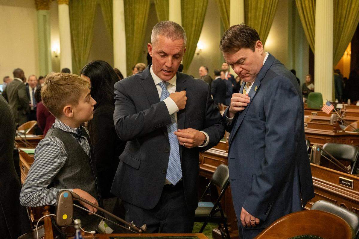Newly elected Assemblymember Carl Demaio, R-San Diego, looks at his legislator pin with partner Johnathan Hale, center, and nephew Harlow Duus, at the state Capitol during the Assembly’s first meeting of the new legislative session on Monday.
